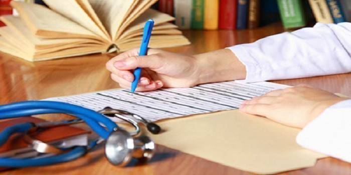 Estetoscópio e médico preenchendo um documento