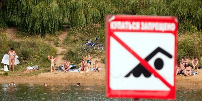 As pessoas têm um descanso na margem de um reservatório