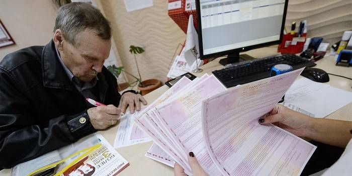 Възрастен мъж и служител на Пенсионния фонд със застрахователни полици в ръце