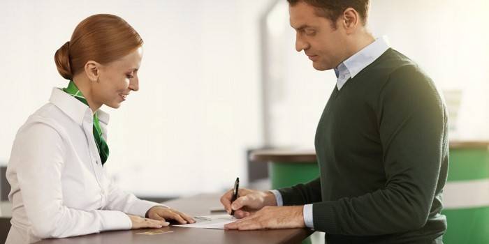 Mężczyzna podpisuje dokumenty w biurze Sberbank