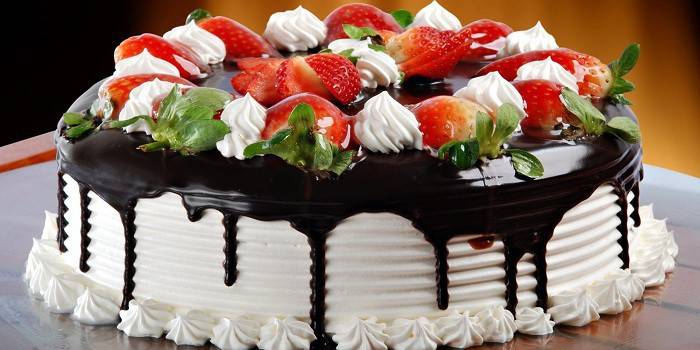 Bolo coberto com chocolate e decorado com bagas no topo