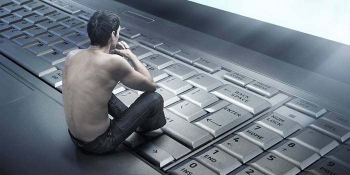 Mała figurka mężczyzny siedzi na klawiaturze laptopa