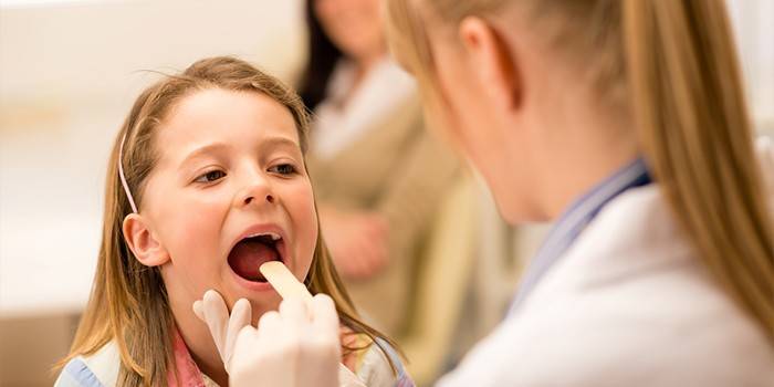 Medic examina la garganta de una niña