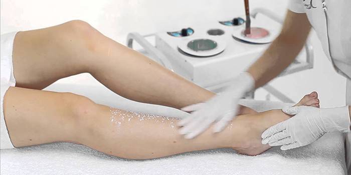 Dziewczyna robi peeling skóry nóg w salonie