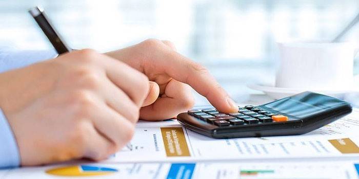 Un hombre hace cálculos en una calculadora.