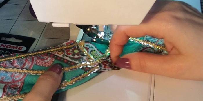 La mujer cose lentejuelas en un hilo a la tela