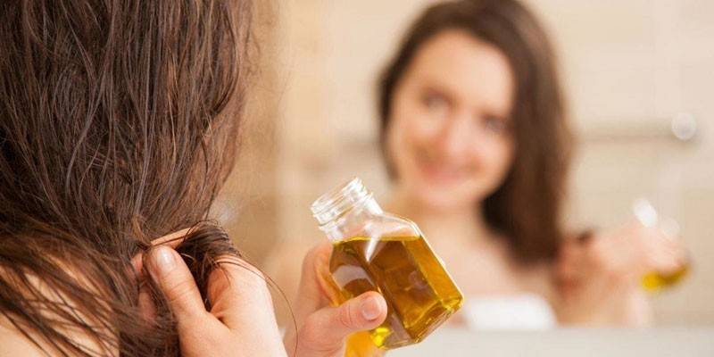 La niña frente al espejo sostiene una botella con aceite en la mano.