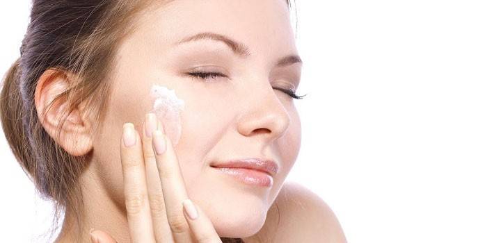 Mujer aplica crema en la cara.