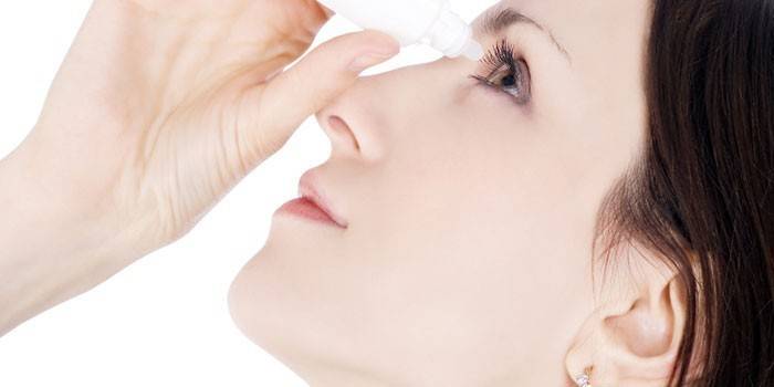 Mujer cae gotas en el ojo