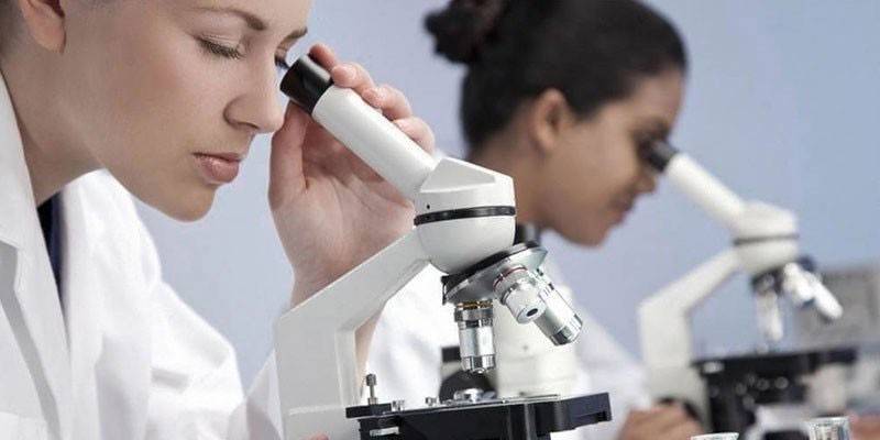 Laboratórni asistenti pod mikroskopmi