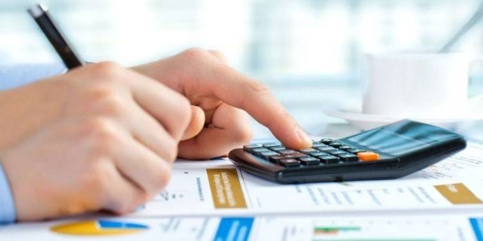 Um homem faz cálculos usando uma calculadora