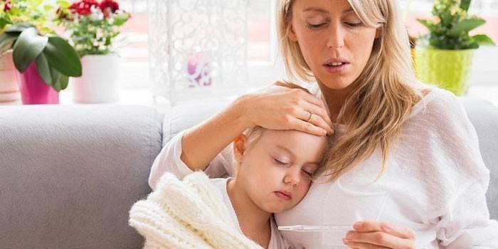 Mamá mira un termómetro y abraza a una niña