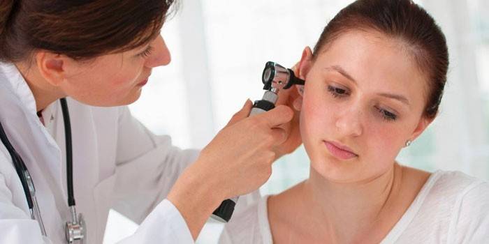 El médico examina el oído de un paciente.
