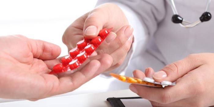 El doctor le pasa las pastillas al paciente