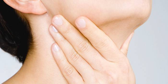 Niña sostiene su mano por la garganta