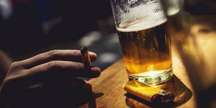 Chica con un cigarrillo y un vaso de cerveza.