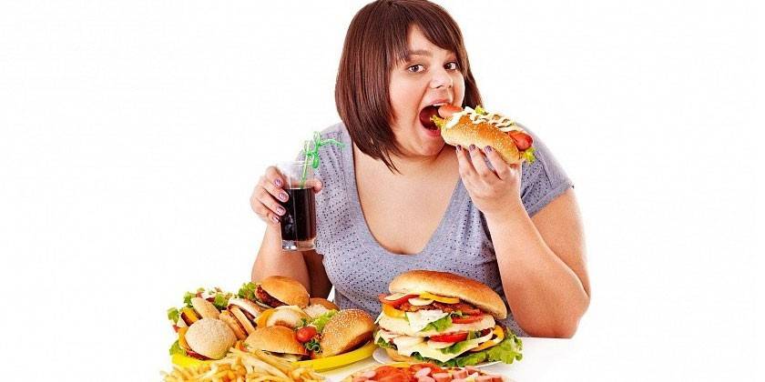 Mujer con sobrepeso comiendo comida chatarra