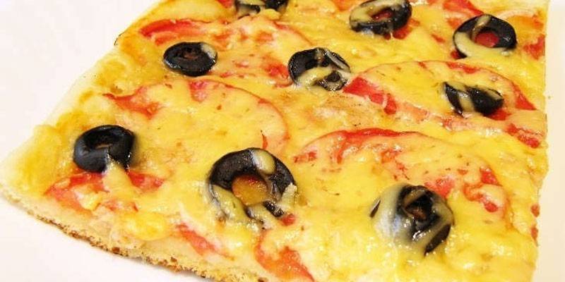 Pizza con piña, aceitunas y tomates.