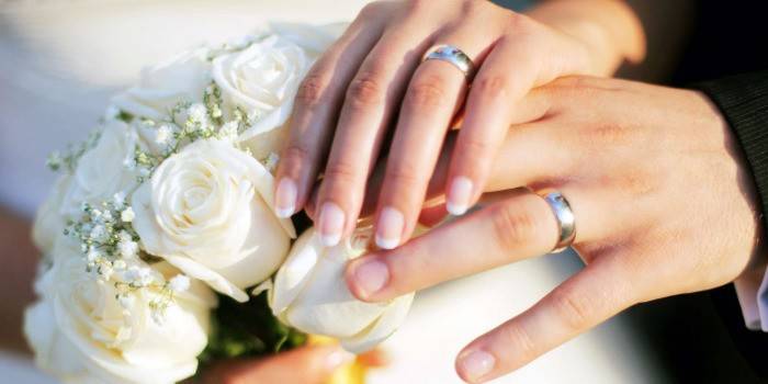 Mãos masculinas e femininas com um buquê de noivas