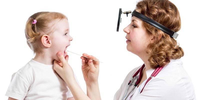 El doctor examina la garganta de una niña.