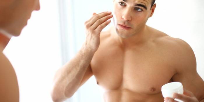 Um homem aplica creme no rosto